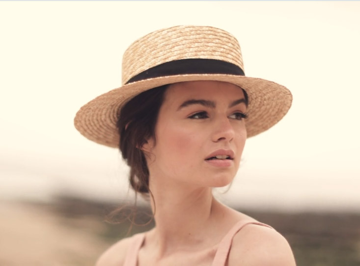 Makeup for fashion shoot video - model wearing straw hat looking out to sea